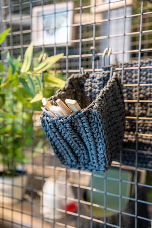 Grey crochet with tie pattern for mini tools and brush hanging on grid metal net background.の写真素材
