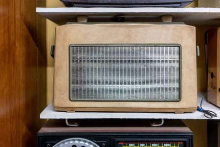 Vintage retro radio on wooden shelf. Retro technology and music concept.