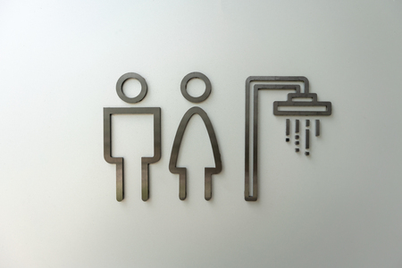 Toilet sign on white wall. Male and female restroom icon made of metal in black.の写真素材