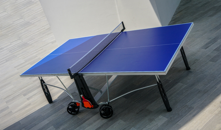Blue table tennis table on wooden floor. Ping-Pong table on outdoor area.