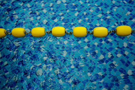 Yellow lanes in blue pool water close-up. Blue pool water and yellow swimming lane marker in swimming poolの写真素材