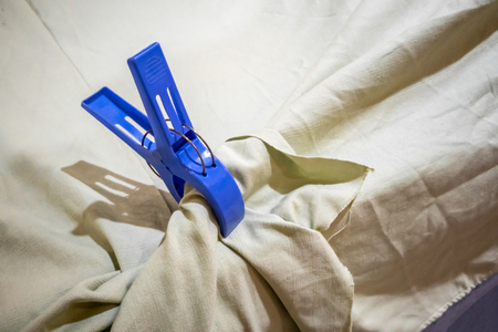 Big blue plastic cloth pin clipped on white table cloth.の写真素材