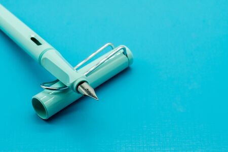 Light blue calligraphic pen on blue background with depth of field.の写真素材