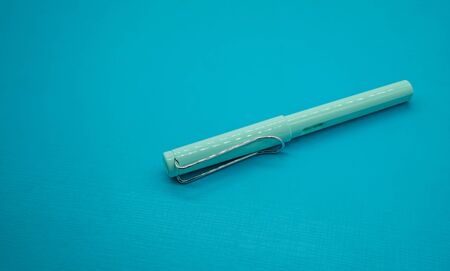 Light blue calligraphic pen on blue background with depth of field.の写真素材