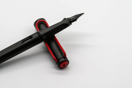 Matte black and red calligraphic or fountain pen on white background with copy space.の写真素材