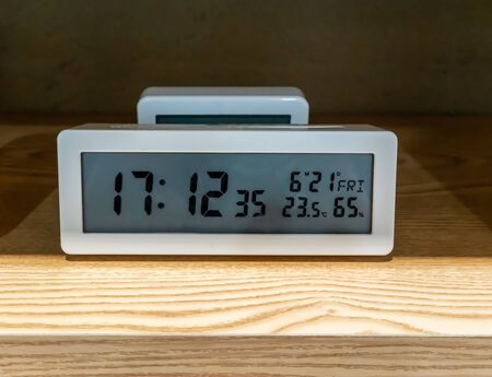 White pocket digital clock on wooden shelf for decorationの写真素材