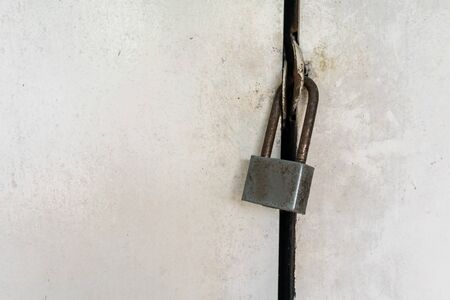 Close-up on rusty silver locked padlock on old dirty white door.の写真素材