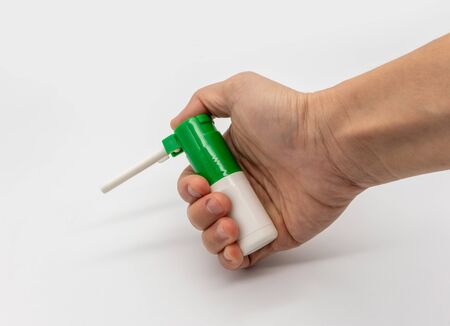 Hand holding throat spray bottle isolated on white background.の写真素材