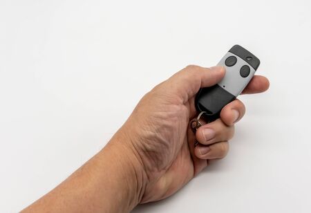 Hand holding house gate remote control in black and grey color isolated on white backgroundの写真素材