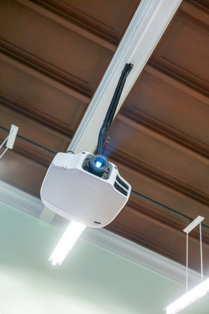 Wood ceiling hanging white projector with metal tube against white backgroundの写真素材