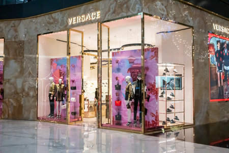 Versace shop display at Icon Siam, Bangkok, Thailand, Nov 28, 2020 : Luxury fashionable clothing and shoes visual merchandising and window shopping in Gold Christmas greeting.のeditorial素材