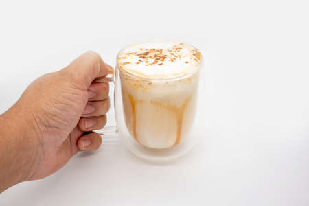 Hand holding hot coffee with milky foam sprinkle with cocoa power for decoration in double wall glass isolated on white background.の写真素材