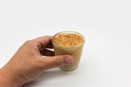 Hand holding dirty coffee on top of cold milk isolated on white background.の写真素材