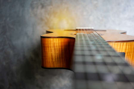 Nylon classical guitar with very shallow depth of field, focus on the cutaway and flame maple body on concrete background.の写真素材