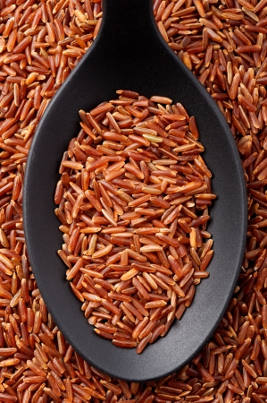 Top view of black spoon full of long grain red riceの写真素材