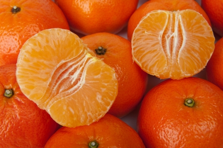 Two parts of a ripe tangerine lie on a heap of tangerines.の写真素材