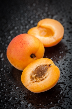 Apricot with halves on black table after rainの写真素材