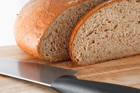 Loaf of bread with knife on wooden board