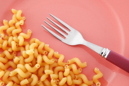 Fork and macaroni on the pink plate. の写真素材