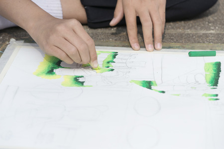 artist hands painting on paper with colorful chalk