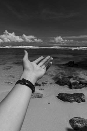 hand in front of beach scene in black and white