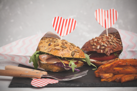 Sandwiches with ciabatta, meat, bacon, vegetables, sweet potato fries and cream sauce. Food for St. Valentine's Day concept.の写真素材