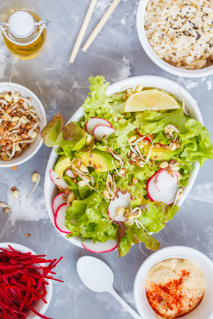 Green vegetable salad with rice, hummus and sprouts, gray background, top view. Healthy detox vegan food concept.の写真素材