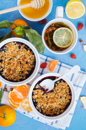 Winter breakfast with berry crumble and tea with lemon. Blue background.の写真素材