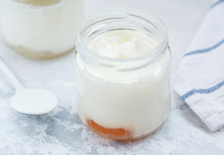 Homemade fruit yogurt in a glass jar on a light background.の写真素材