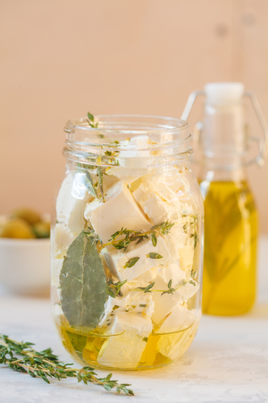 Feta cheese with olive oil and herbs in a glass jar.の写真素材