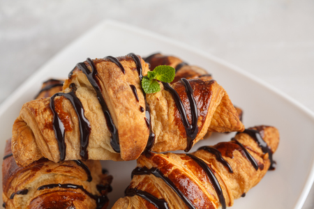 Fresh croissants with chocolate syrup on a light gray background, copy space. French cuisine dessert concept.の写真素材