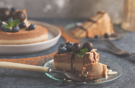 piece of raw vegan chocolate caramel cheesecake with blueberries, raw almonds and candy beads....