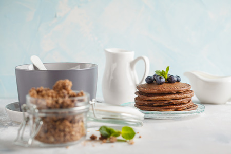 Chocolate pancakes, chocolate baked granola in a jar and milk. Healthy breakfast concept.の写真素材