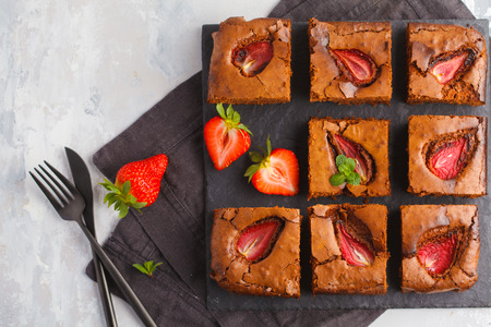 Homemade dark chocolate brownie with strawberries on a slate, a top view, copy space.の写真素材