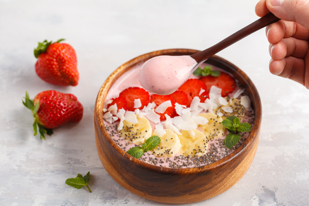 Strawberry pink smoothies bowl with banana, coconut and chia seeds. Healthy vegan food concept.の写真素材