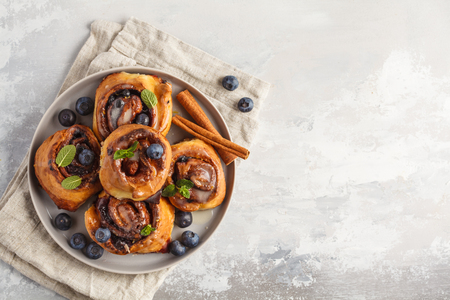 Homemade cinnamon buns with blueberries and cinnamon on gray plate, breakfast backgroundの写真素材