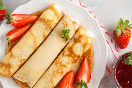 Thin hot pancakes with cottage cheese and strawberries. Healthy traditional breakfast concept.の写真素材