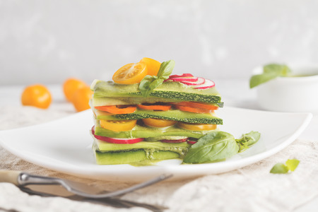 Raw zucchini lasagna with vegetables and pesto sauce, light background. Vegetarian raw diet concept.の写真素材