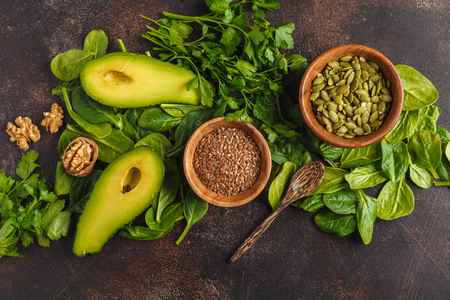 Green salad, vegan ingredients: spinach, avocado, flax and pumpkin seed. Food background. Detox vegan healthy eating concept. Top view, copy space.の写真素材