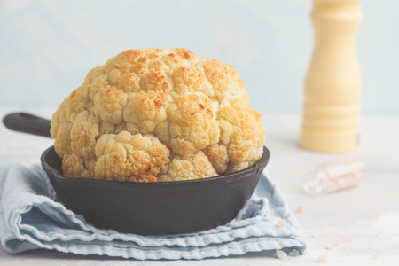 Whole baked cauliflower in a cast-iron frying pan. Healthy vegan food concept.の写真素材