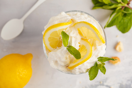 Lemon dessert, lemon trifle, cheesecake, whipped cream, parfait. Fruit mousse in glass on a light...