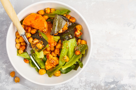 Salad with baked pumpkin and chickpeas with mustard-honey dressing in a white plate, copy space, top view. Healthy vegan food concept.の写真素材