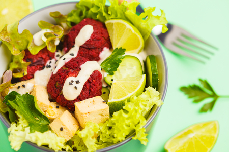 Vegan buddha bowl with beetroot meatballs, vegetables, tahini dressing and baked tofu. Healthy vegan food concept.の写真素材