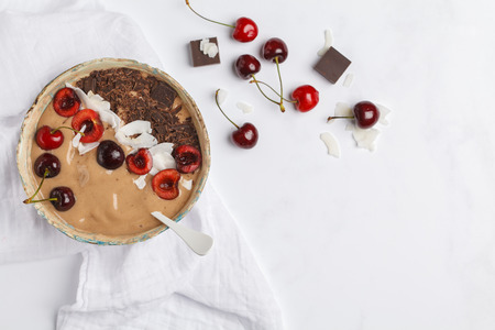 Chocolate - cherry smoothie bowl with coconut and bananas on white background, top view. Healthy vegan food concept. Raw vegan lifestyle.の写真素材