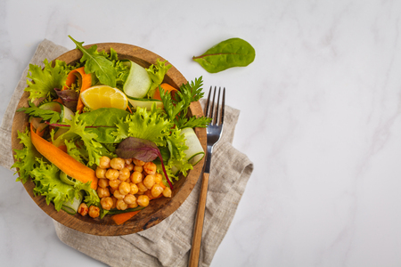 Summer vegetable salad with chickpeas in a wooden bowl. Healthy vegan food concept.の写真素材