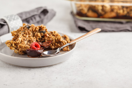 Crumble cake with plum and raspberries in a glass dish. Healthy vegan food concept.の写真素材