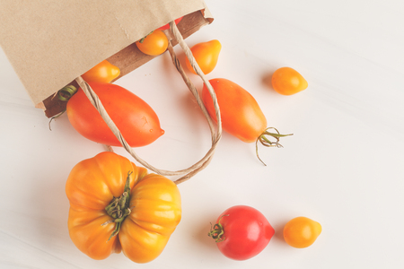 Different types of tomatoes in a paper bag, white background. Clean eating concept.の写真素材