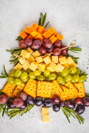 Christmas tree from appetizers: cheese, grapes, crackers. Christmas food concept, white background.の写真素材
