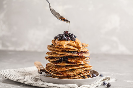 Stack vegan blueberry pancakes with peanut butter and syrup. Clean eating concept.
