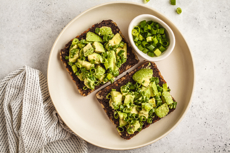 Avocado toast with whole wheat bread, avocado and green onion on a white plate. Clean eating concept.の写真素材